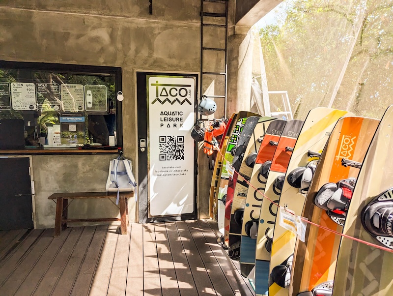 Entrance to Taco Lake with wakeboards for rent on display and some prices visible at the ticket office.