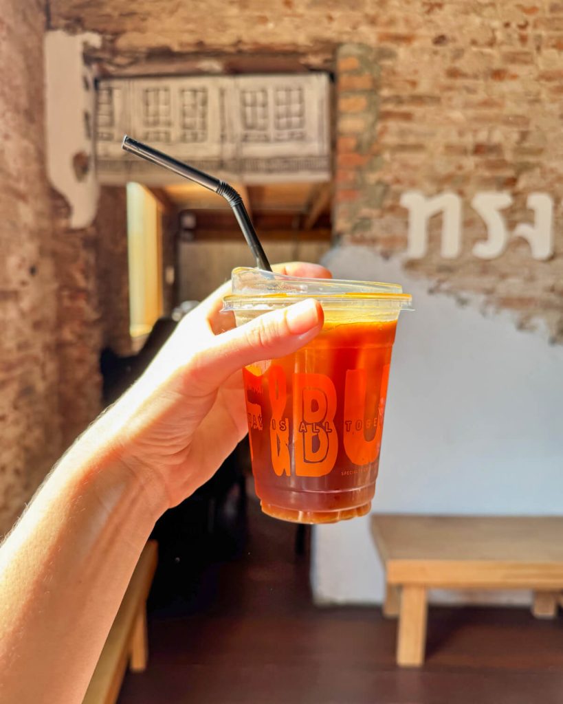 Sunny day with light streaming in through a window at Koff and Bun and lighting up an orange espresso americano with an exposed brick vibe in the background