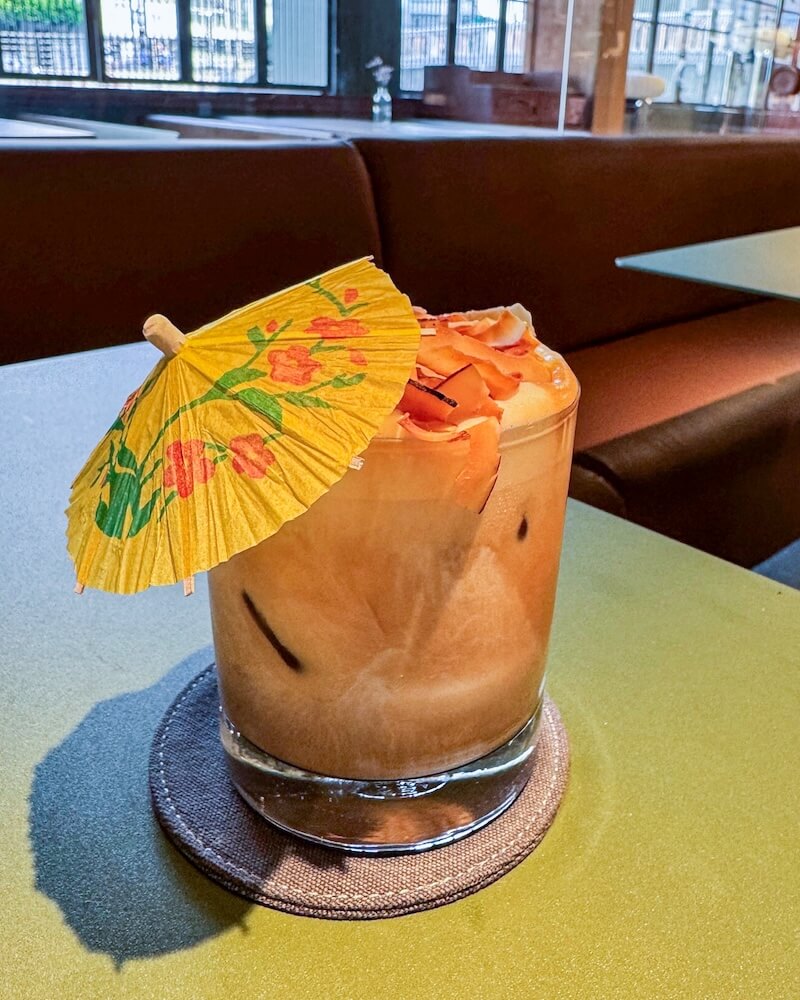 An iced coffee with coconut milk and an umbrella giving it a tropical feel