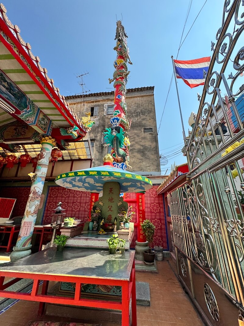 Towering dragon pillar at Hok Lien Keng shrine on a sunny day with the Thai flag visible