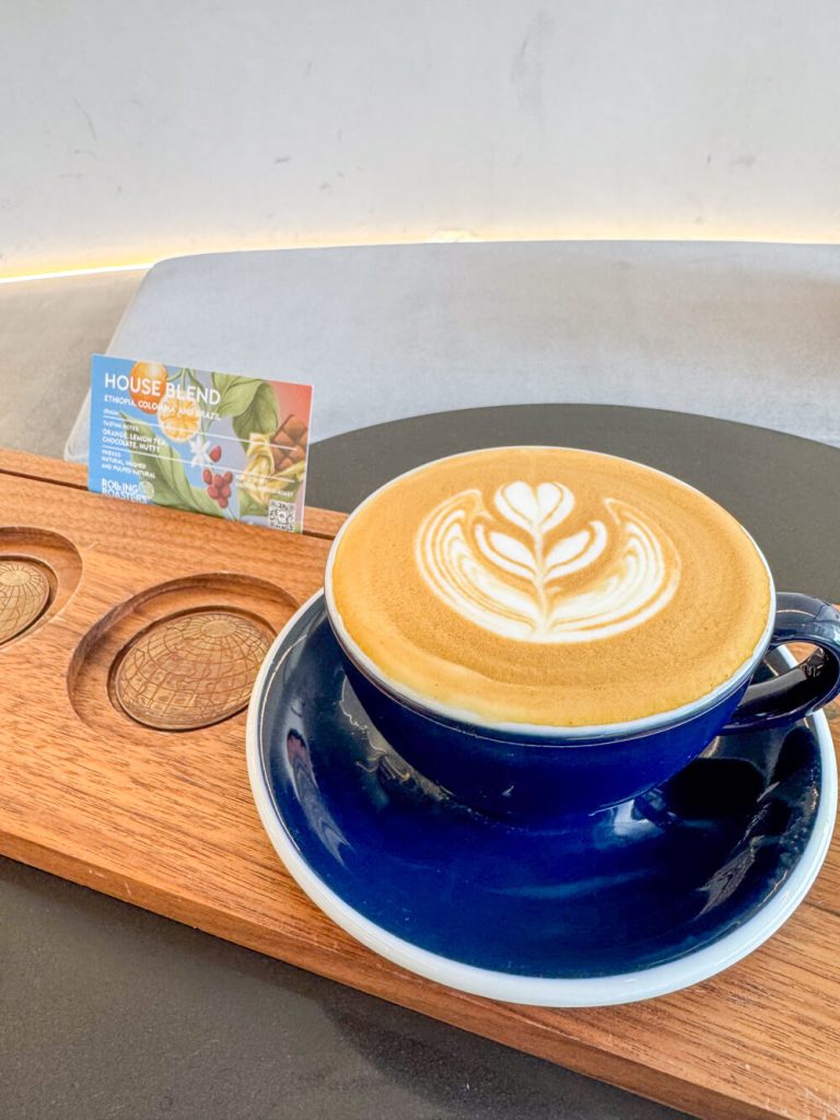 A cup of coffee served in Ekkamai with a little sign about the beans used in the coffee
