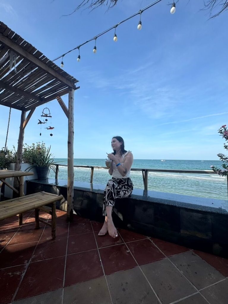 Allison Green sitting at cafe in front of the beach
